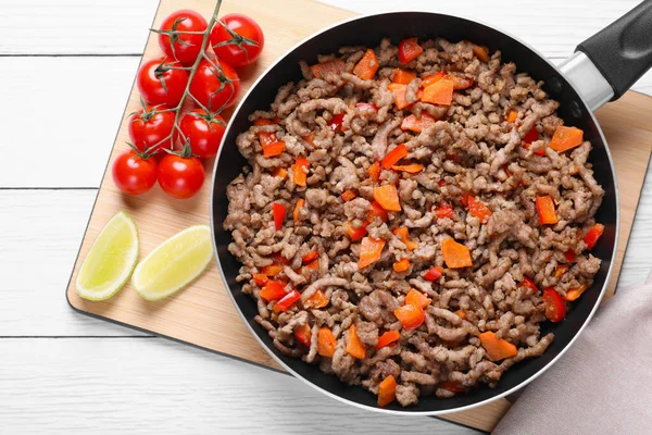 Delicious minced meat with carrot, pepper and tomatoes on white wooden table, flat lay