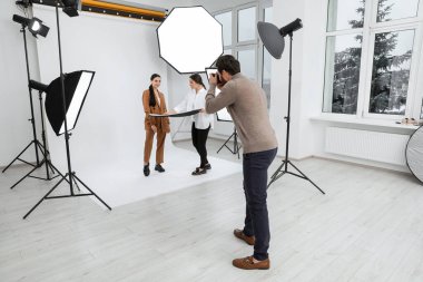 Professional photographer and assistant working with beautiful model in modern photo studio