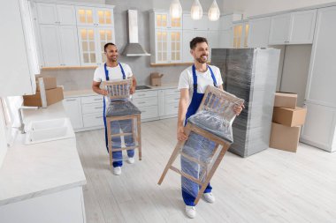 Male movers carrying chairs in new house