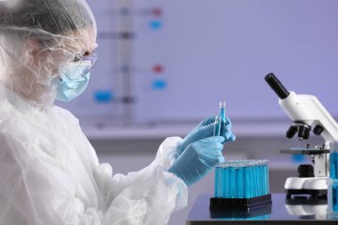 Scientist working with test tubes of light blue liquid in laboratory