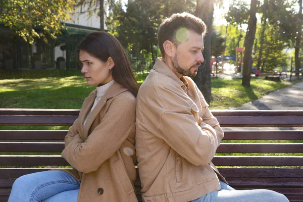 Upset arguing couple sitting on bench in park. Relationship problems