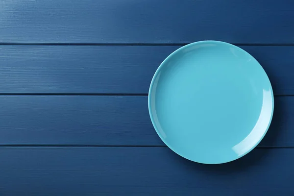 Clean plate on wooden blue table, top view. Space for text
