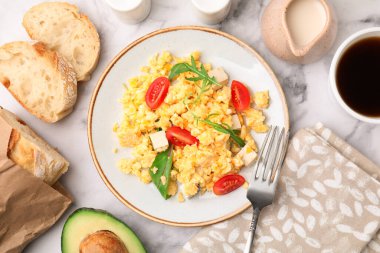 Delicious scrambled eggs, tofu and tomatoes served on white marble table, flat lay