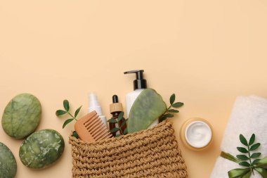 Preparation for spa. Compact toiletry bag with different cosmetic products, sea salt and towel on beige background, flat lay. Space for text