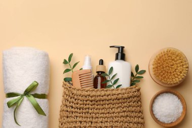 Preparation for spa. Compact toiletry bag with different cosmetic products, sea salt and towel on beige background, flat lay. Space for text
