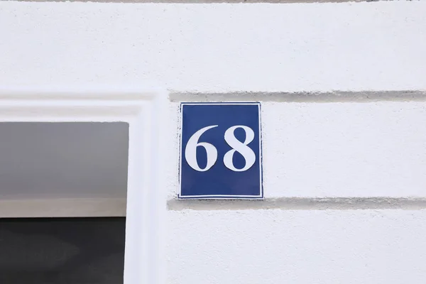 Plate with house number sixty eight on white building outdoors