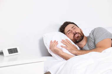 Man sleeping on comfortable pillows in bed at home