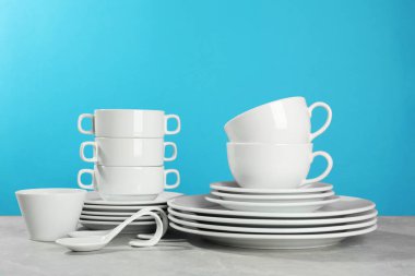 Set of clean dishware on grey table against light blue background