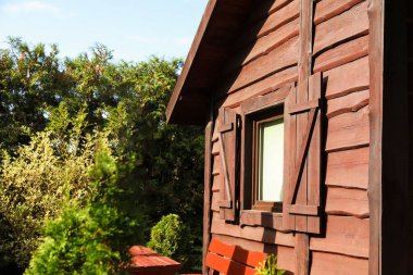Exterior of cozy wooden house surrounded by lush nature on sunny day, closeup