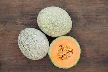 Whole and cut fresh ripe melons on wooden table, flat lay