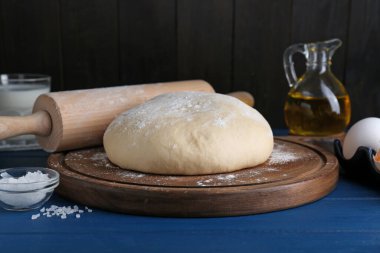 Fresh yeast dough and ingredients on blue wooden table