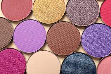 Different beautiful eye shadows on beige background, flat lay
