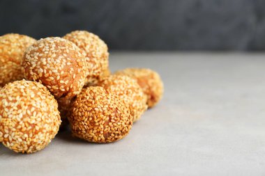 Delicious sesame balls on light grey table, closeup. Space for text