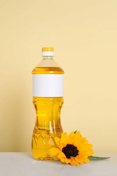 Bottle of cooking oil and sunflower on white table