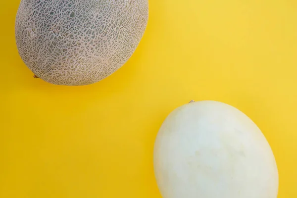 Different tasty ripe melons on yellow background, flat lay