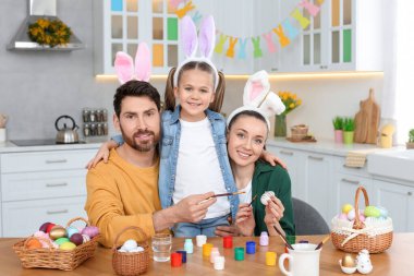 Happy family with Easter eggs at table in kitchen