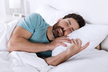 Man sleeping on comfortable pillows in bed at home