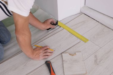 Man using measuring tape during installation of laminate flooring, closeup