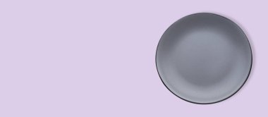 Empty gray ceramic plate on violet background, top view and space for text. Banner design