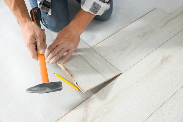 Professional worker using hammer during installation of new laminate flooring, closeup