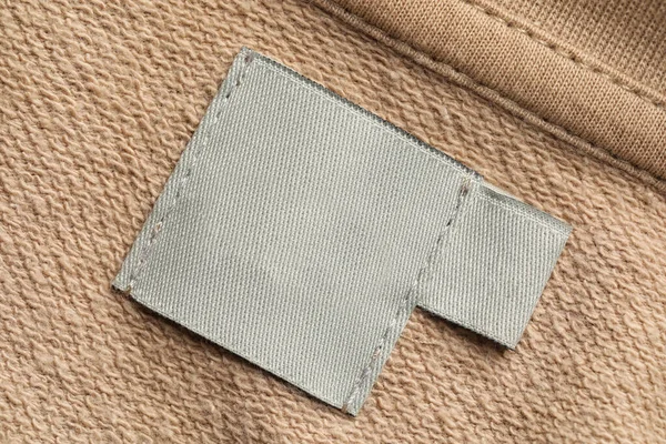 Clothing label on beige garment, top view