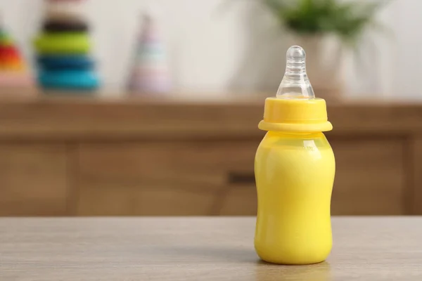 Feeding bottle with baby formula on wooden table indoors. Space for text