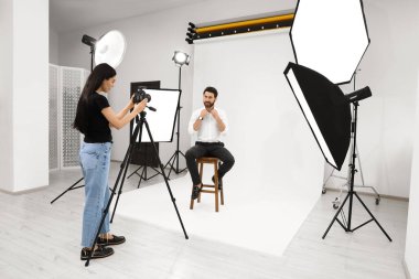 Professional photographer working with handsome model in modern photo studio