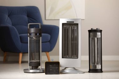 Different modern infrared heater on floor in cozy room