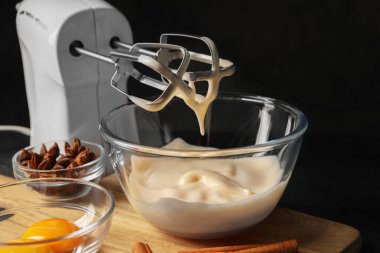 Different ingredients and mixer on black table. Cooking delicious eggnog
