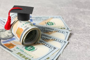 Scholarship concept. Graduation cap and banknotes on light grey table, closeup