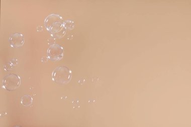 Many beautiful soap bubbles on light brown background. Space for text