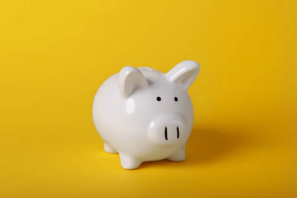 Ceramic piggy bank on yellow background. Financial savings