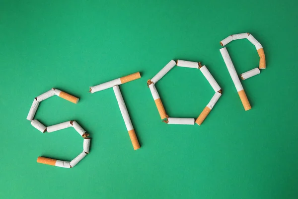 単語を停止緑色の背景に壊れたタバコで作られ フラットレイアウト 喫煙の概念を止める — ストック写真