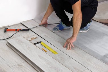 Kapalı alanlara yeni kaplama döşemeler döşeyen adam.