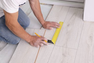 Man using measuring tape during installation of laminate flooring, closeup