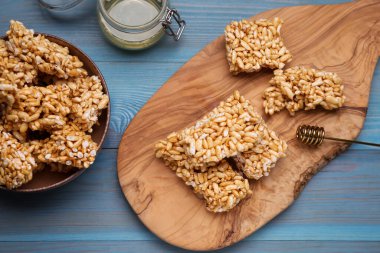 Puffed rice bars (kozinaki) on light blue wooden table, flat lay