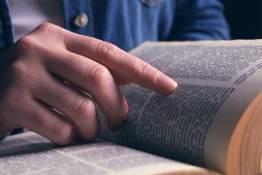 Woman reading holy Bible on black background, closeup