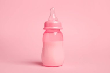 One feeding bottle with milk on pink background