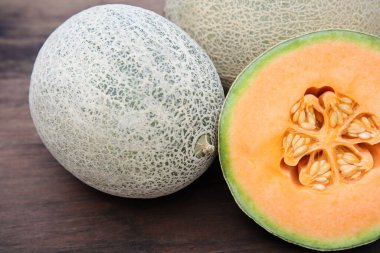 Whole and cut fresh ripe melons on wooden table, closeup