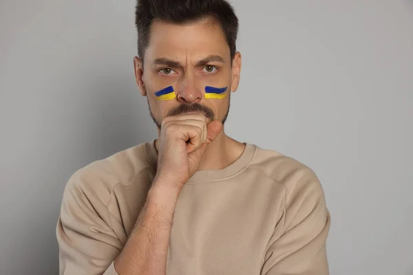 Homem Irritado Com Desenhos Bandeira Ucraniana Rosto Contra Fundo Cinza — Fotografia de Stock