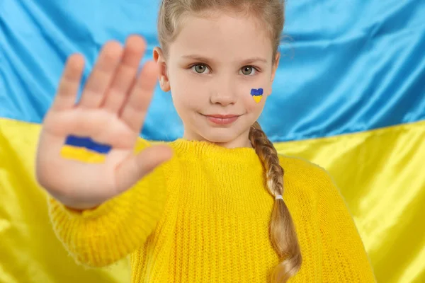 Menina Com Tinta Mão Rosto Perto Bandeira Ucraniana — Fotografia de Stock