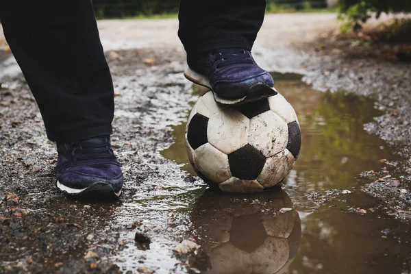 Man with soccer ball in muddy puddle outdoors, closeup