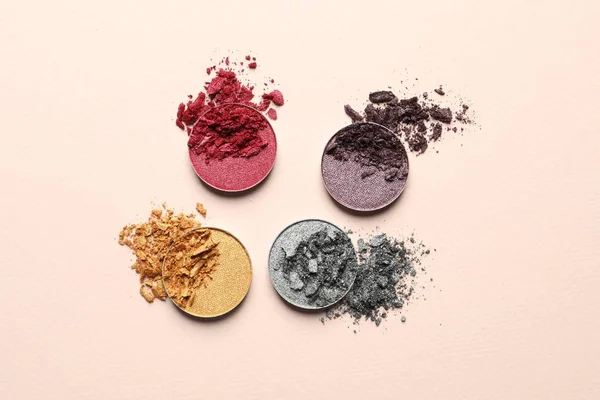 Different crushed eye shadows on beige background, flat lay