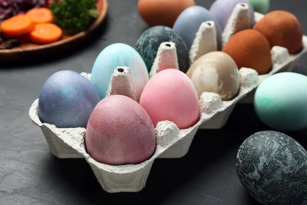 Easter eggs painted with natural organic dyes on black table, closeup