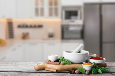 Mortar and different spices on wooden table in kitchen. Space for text