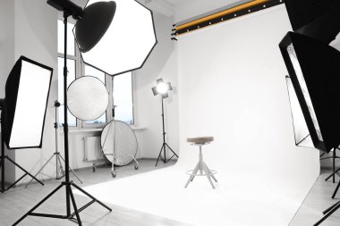 Interior of modern photo studio with bar stool and professional lighting equipment