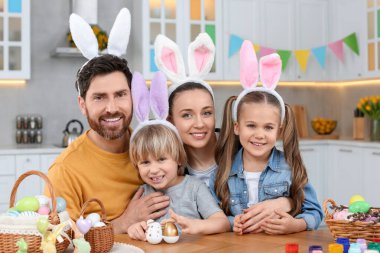 Happy family with Easter eggs at table in kitchen