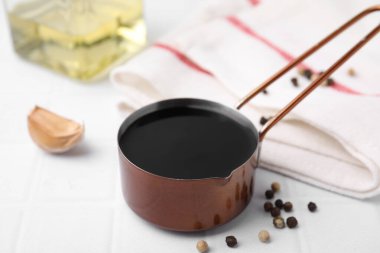 Metal small saucepan with balsamic vinegar and ingredients on white table