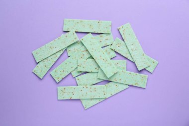 Many sticks of tasty chewing gum on violet background, flat lay