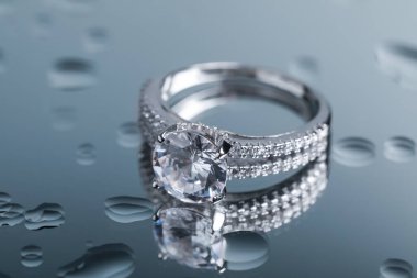 Luxury jewelry. Stylish presentation of elegant ring on mirror with water drops, closeup